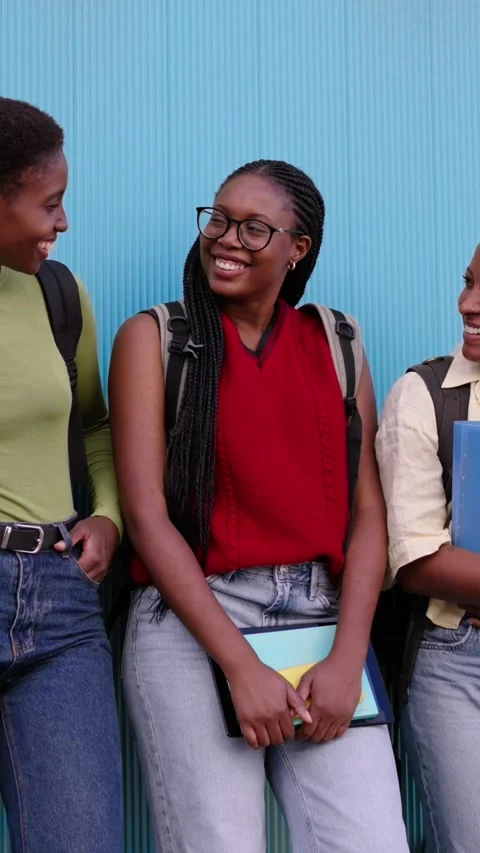 Three black female students standing holding folders looking joyful at each Stock Footage 268644799