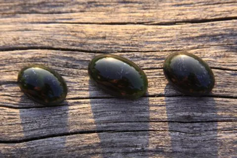 Three black jade translucent gemstones on wood Stock Photos
