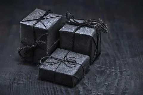Three black paper boxes on black wooden background, close up, concept of blac Foto stock