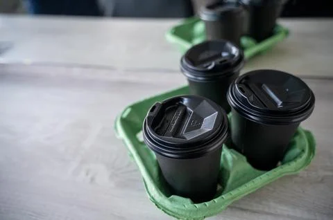 Three black plastic glasses with a drink stand on a light wooden table in the Stock Photos