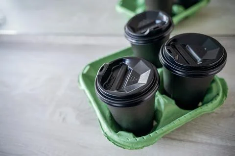 Three black plastic glasses with a drink stand on a light wooden table in the Stock Photos