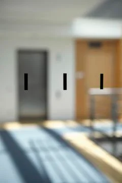 Three black rectangles on a window pane with office walkway seen in background 스톡 사진