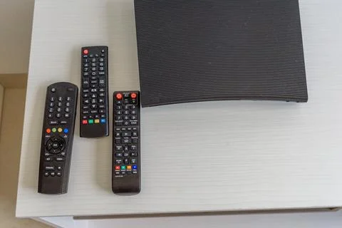 Three black remote controls and dvd player top view Stock Photos