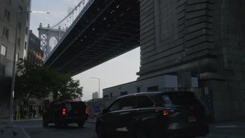 Three black vehicles drive below The Manhattan Bridge Stock Footage 278334240
