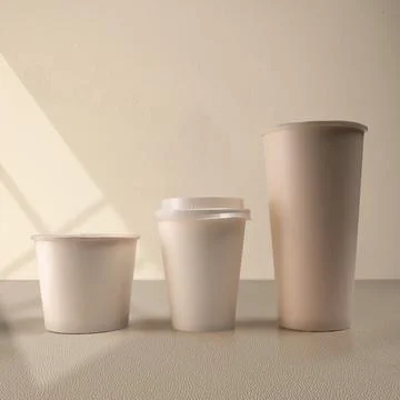 Three blank beige paper cups of different sizes lined up on a neutral surfa.. Stock Photos