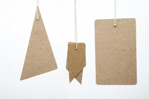 Three blank brown kraft paper tags in various geometric shapes hanging agai.. Stock Photos