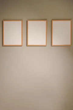 Three blank wooden frames hanging on a neutral gray wall offering copy spac.. Stock Photos