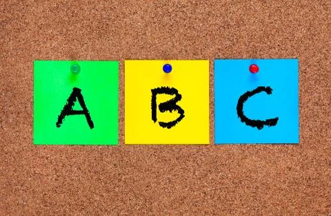 Three blanks post-it notes on cork board with letters ABC. Stock Photos