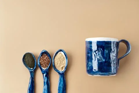 Three blue ceramic clay handmade spoons with flax seeds, chlorella powder, maka Stock-Fotos