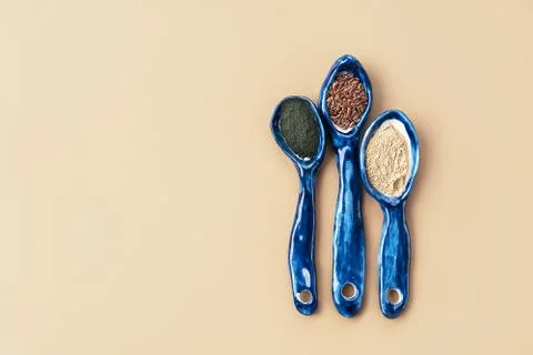 Three blue ceramic clay handmade spoons with flax seeds, chlorella powder, maka Stock Photos