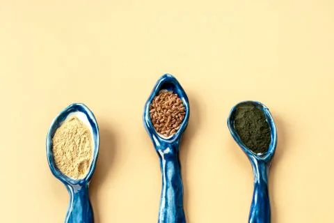 Three blue ceramic clay handmade spoons with flax seeds, chlorella powder, maca Stock Photos