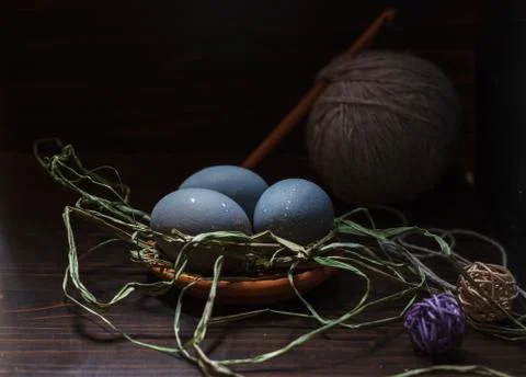 Three blue Easter eggs on a ceramic saucer on a dark background Stock Photos