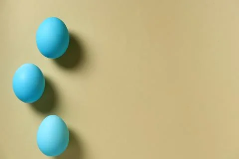 Three blue eggs placed on a light brown surface during daylight in a simple Stock-Fotos