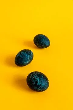 Three blue eggs on a yellow background. Feast of Bright Easter. Stock Photos