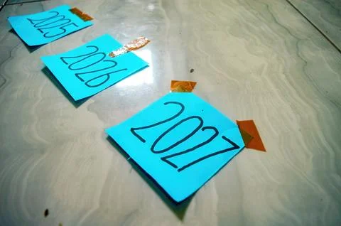 Three blue sticky notes labeled 2015, 2016, and 2017 taped to tiled floor w.. Stock-Fotos