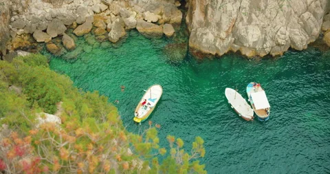 Three boats floating in clear green water near rocky cove in Capri, Italy Vídeo Stock 313093491