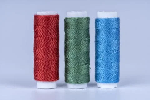 Three bobbins of sewing thread of red green and blue colors isolated on white Stock Photos