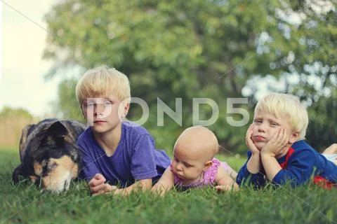 Three Bored Young Children and Dog Relaxing Outside Stock Photos