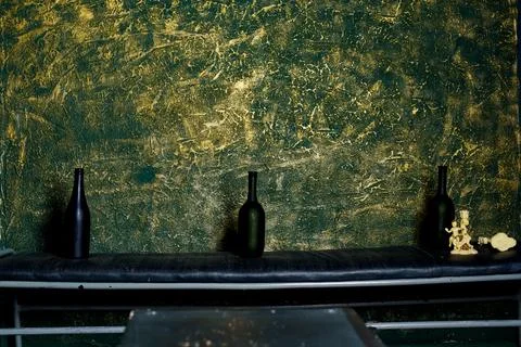 Three bottles are placed on a long table against a textured wall. The setting Stock Photos
