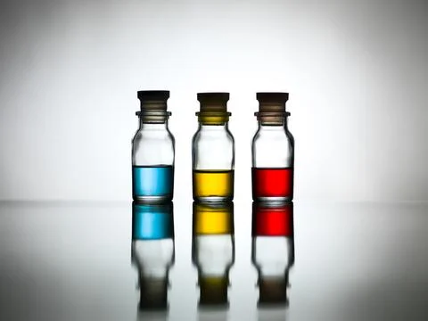 Three bottles with colored solution on table Foto stock