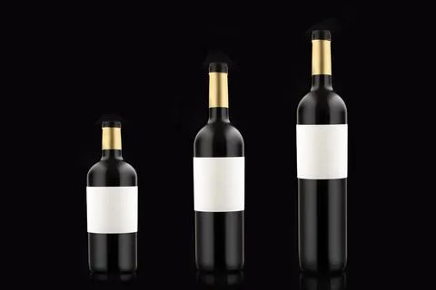 Three bottles of red wine with empty labels of different volume and size on a Stock-Fotos