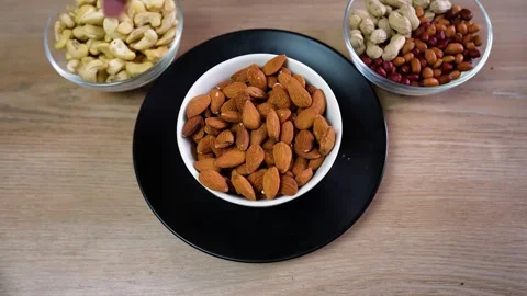 Three bowls of assorted nuts on a wooden table Stock Footage 320726932