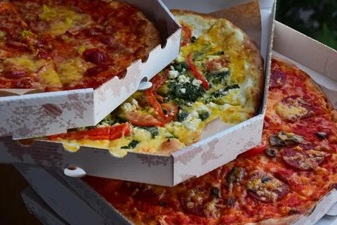Three boxes of pizza of different types lie one on top Stock Photos