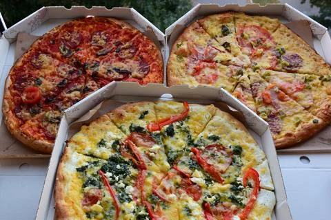 Three boxes of pizza of different types lie next to each other Stock Photos