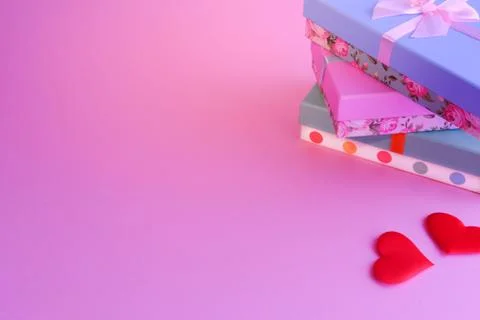 Three boxes in a stack are tied with a ribbon. Nearby are two red hearts on a Stock Photos