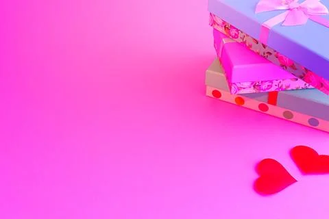 Three boxes in a stack are tied with a ribbon. Nearby are two red hearts on a Stock Photos