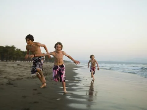 Three boys playing on beach Stock Photos