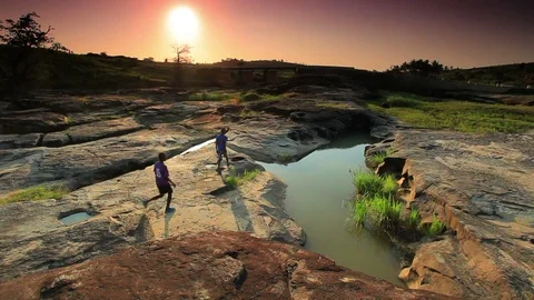 Three boys walking away from the camera down a dried up riverbed Stock Footage 74096991
