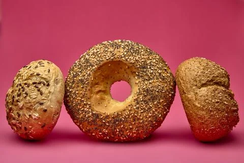 Three bread rolls including a bagel on pink background Stock Photos