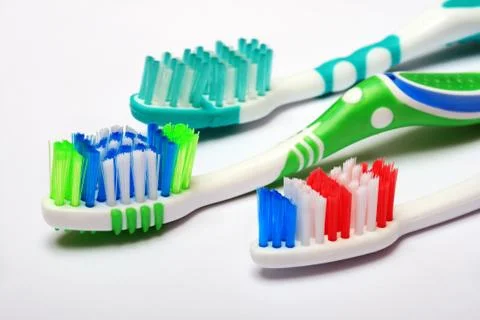 Three bright color tooth-brushes on a light background Stock Photos