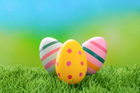 Three bright Easter eggs in retro style on a green meadow. Stock-Fotos