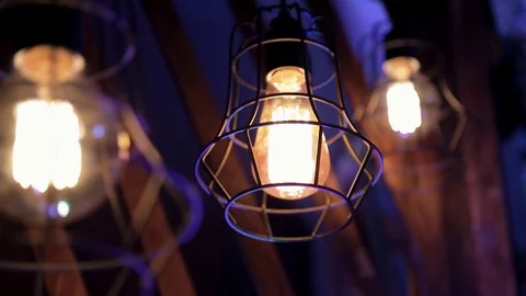Three bright lanterns in metal grilles burn in the blue twilight Stock Footage 74220964
