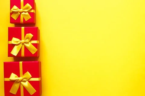Three bright red gift boxes on yellow background Stock Photos