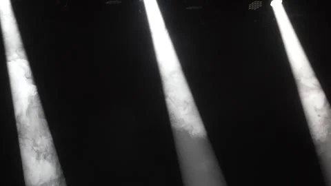 Three bright white spotlights shining through smoke dark stage Stock Footage 346331051