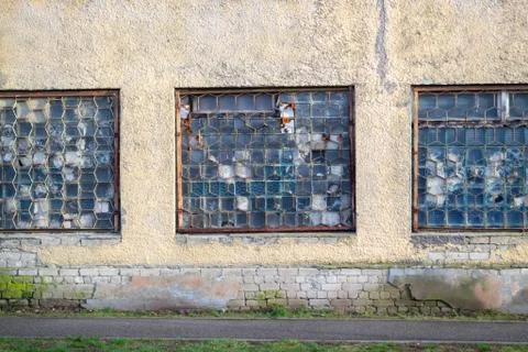 Three broken windows and a grill on them. Large old windows of an abandoned f Stock Photos