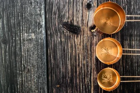 Three of bronze  measuring cups on old wood table background  in top view Stock Photos