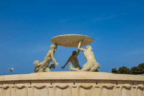 Three bronze Tritons supporting a large platter in the modernist fountain n.. Stock Photos