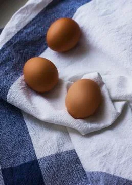 Three brown chicken eggs on a white dish towel Stock Photos