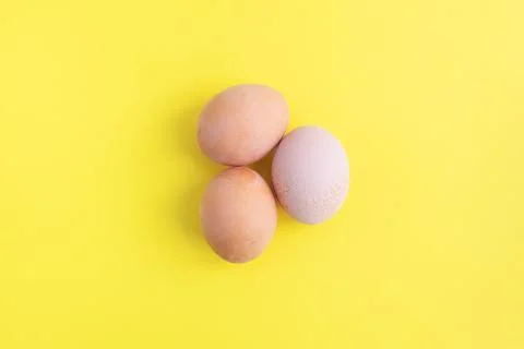 Three brown chicken eggs on a yellow background. Top view, copy space. Stock-Fotos
