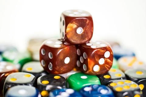 Three brown copper dice sitting on colored dice Stock Photos