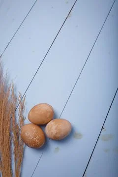 Three brown Easter eggs on blue wooden background. Place for text, vertical Stock Photos