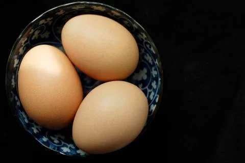 Three brown eggs in blue patterned bowl Stock Photos