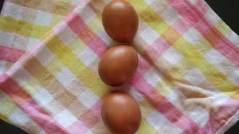 Three brown eggs in a vertical row on pastel cloth Stock Photos