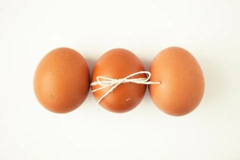 Three brown eggs wrapped with thread on white background Stock Photos