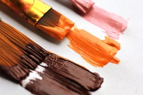 Three brushes of different size leaving acrylic paint strokes on white Stock Photos