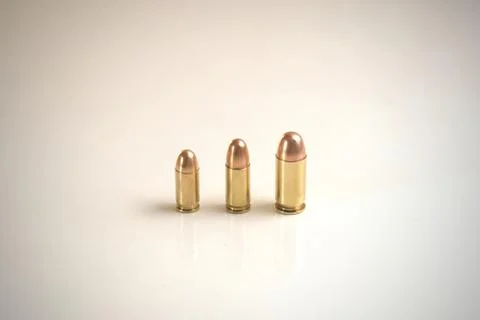 Three bullets of different calibers on a white surface. Stock Photos